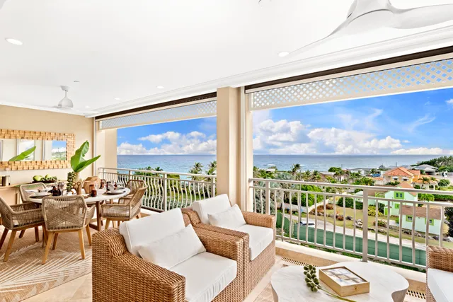 Villa balcony and outdoor dining lounge overlooking the ocean at Poinciana